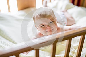 Close-up portrait of a crying cute baby in the crib at home