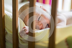 Close-up portrait of a crying cute baby in the crib at home