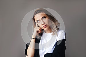 Close up portrait of curly blonde confident thoughtful girl, holding hand near the face