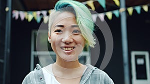 Close-up portrait of cute Asian hipster with dyed hair and nose piercing outside