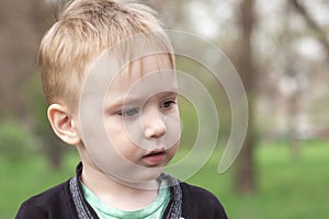 Close up portrait of cute Ð¡aucasian baby boy on green park background.