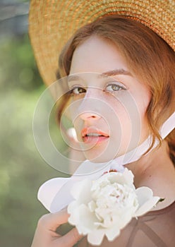 Close-up portrait of a cute blonde in a straw hat at sunset. Vintage tone..Soft blur background