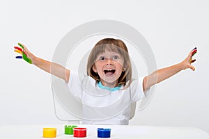 Close-up portrait of a cute cheerful happy smiling little girl draws her own hands with gouache or finger paints isolated on white