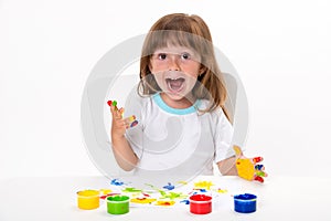 Close-up portrait of a cute cheerful happy smiling little girl draws her own hands with gouache or finger paints isolated on white