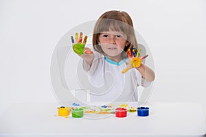 Close-up portrait of a cute cheerful happy smiling little girl draws her own hands with gouache or finger paints isolated on white