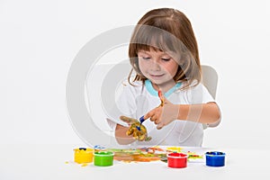 Close-up portrait of a cute cheerful happy smiling little girl draws her own hands with gouache or finger paints isolated on white