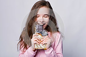 Close up portrait of cute girl eating Chocolate over grey background and smile