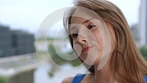 Close-up. Portrait of a cute girl with long hair against the backdrop of a city landscape. A girl smile and straightens