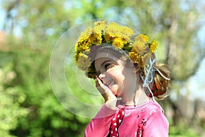 Close up portrait of a cute laughing two years old girl wearing a dandelion wreath