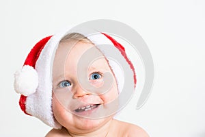 Close up portrait of a cute little baby with red Santa Claus hat isolated on white background. Small smiling kid face with blue