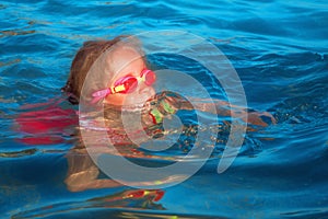 Close up portrait of cute little child girl in the sea learn to swim.  Summer vacation and healthy lifestyle concept