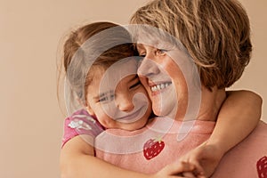 Close up portrait of cute little granddaughter hugging her beautiful grandmother, enjoying leisure time together