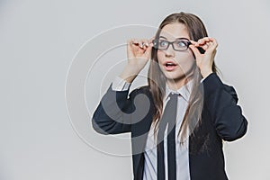 Close up portrait of a dazzling and astounded businesswoman, who is touching the black rim of glasses with both hands