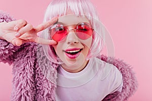 Close-up portrait of debonair girl in trendy peruke. Indoor shot of laughing young woman in sunglas