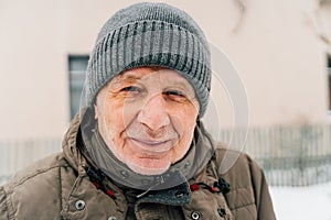 Close-up portrait of delighted old man in warm clothes is standing outdoors and laughing