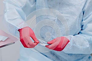 Close up portrait of dentist hands in sterile gloves exposes new tool. Dentist at work.