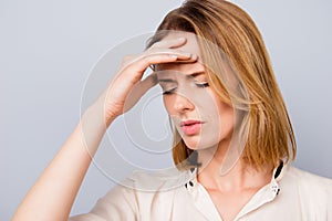 Close up portrait of dipressed young woman with short blonde hair having headache and touching her forehead