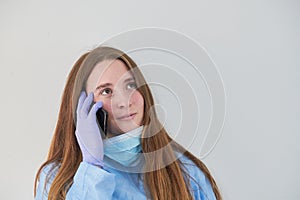 A close-up portrait of a doctor wearing an operating theatre outfit and brazing a teddy bear - isolated on a blue background.