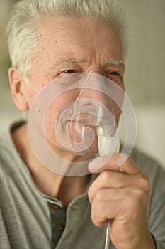 Close-up portrait of an elder man making inhalation