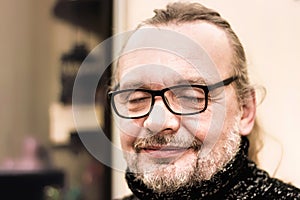 Close-up portrait of an elderly man praying or dreaming with his eyes closed. A stylish, happy old man with glasses