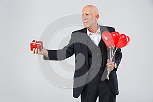 Close-up portrait of an elderly man on a white background, in the studio, in a black smart suit with balls in his hand