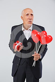 Close-up portrait of an elderly man on a white background, in the studio, in a black smart suit with balls in his hand