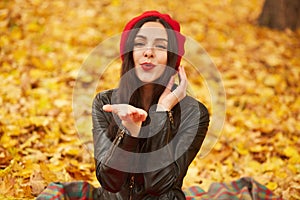 Close up portrait of elegant pretty brunette woman posing at autumn bright day in city park, wearing elegant red beret and stylish