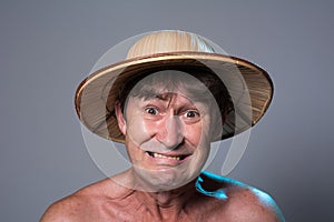 Close-up portrait of an embittered man with a naked torso in a hat