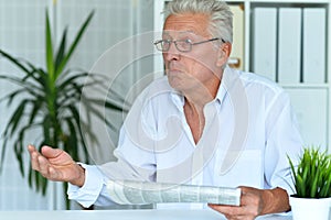 Close up portrait of emotional senior man reading newspaper