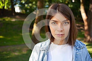 Close-up portrait European young brunette student female outdoor, wearing white t-shirt and denim jacket