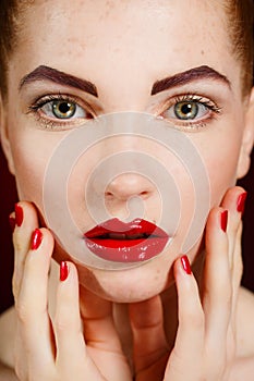 Close-up portrait of european young woman model with glamour make-up and red bright manicure. christmas makeup, bloody red li