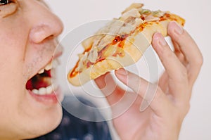 Close up portrait of excited happy hungry young man eating a piece of pizza, focus pizza