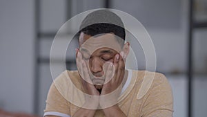 Close-up portrait of exhausted African American young man sighing looking at camera holding business graphs. Tired