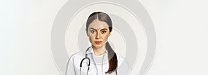 Close up portrait, face of young woman doctor with stethoscope, looking serious, professional healthcare worker in