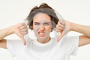 Close up portrait, face of young woman that is showing thumbs down, dislike, do not recommend gesture, express negative