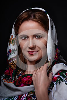 Close up portrait of fashion beautiful Russian style woman in traditional scarf on black background. Studio shot