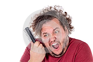 Close up portrait of fat man tries to comb his tangled and naughty hair with a small black comb isolated on white background