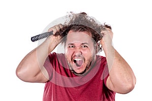 Close up portrait of fat man tries to comb his tangled and naughty hair with a small black comb isolated on white background