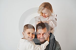 Close-up portrait of father, son and daughter. Happy family hugging and smiling on white background. Paternity. Single photo