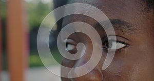 Close-up portrait of female eyes looking sidewards and blinking while African American woman watching city outdoors