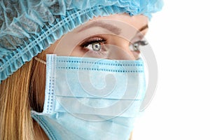 Close up portrait of female medical doctor or nurse wearing protective cap and mask. Surgery, medical assistance, hospital,