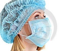 Close up portrait of female medical doctor or nurse wearing protective cap and mask. Surgery, medical assistance, hospital