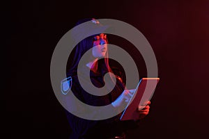 Close-up portrait of a female police officer posing for the camera against a black background with red and blue