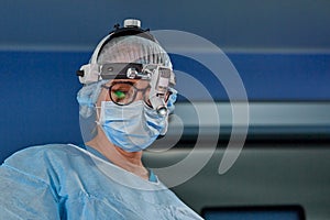 Close up portrait of female surgeon doctor wearing protective mask and hat during the operation. Healthcare, medical