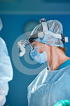 Close up portrait of female surgeon doctor wearing protective mask and hat during the operation. Healthcare, medical