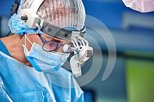 Close up portrait of female surgeon doctor wearing protective mask and hat during the operation. Healthcare, medical