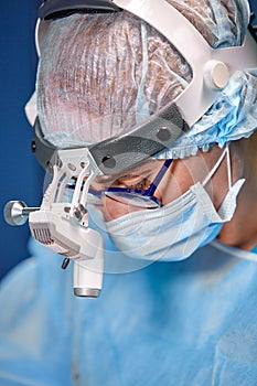 Close up portrait of female surgeon doctor wearing protective mask and hat during the operation. Healthcare, medical