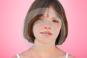 Close up portrait of freckled stylish small kid looks with narrow dark eyes directly into camera, has serious expression, isolated photo