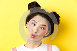 Close up portrait of funny asian teen girl with glamour makeup and hairstyle, squinting eyes and pucker lips silly