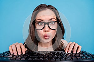 Close-up portrait of funny focused female working on new project typing keyboard isolated on blue color background